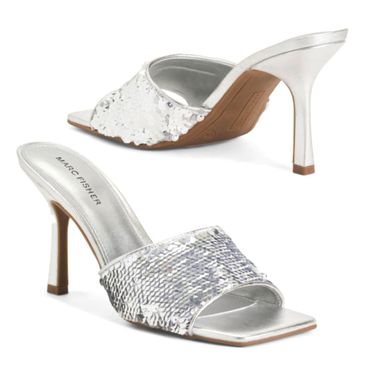 A pair of Marc Fisher Women's Danria Sequin Dress Slip-on Sandals with silver sequin embellishment and a stiletto heel. One sandal is displayed in silver, and the other in a brown-toned sequin finish.